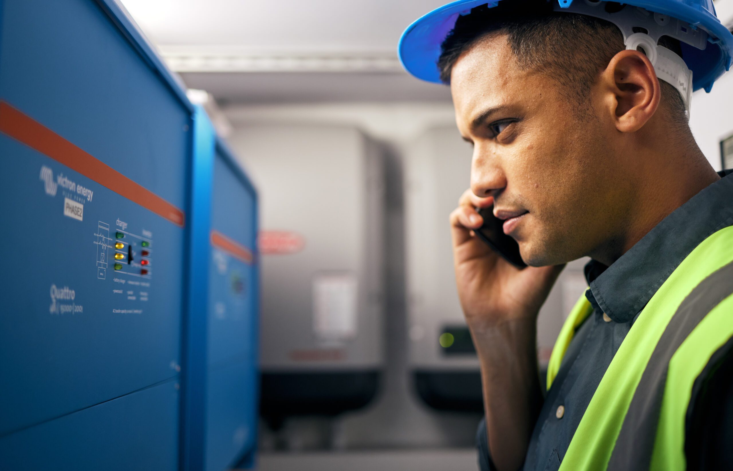 Phone call, man and technician working in control room or engineering service on switchboard, power box or maintenance on generator. Electrician, construction worker and check on inverter and advice.